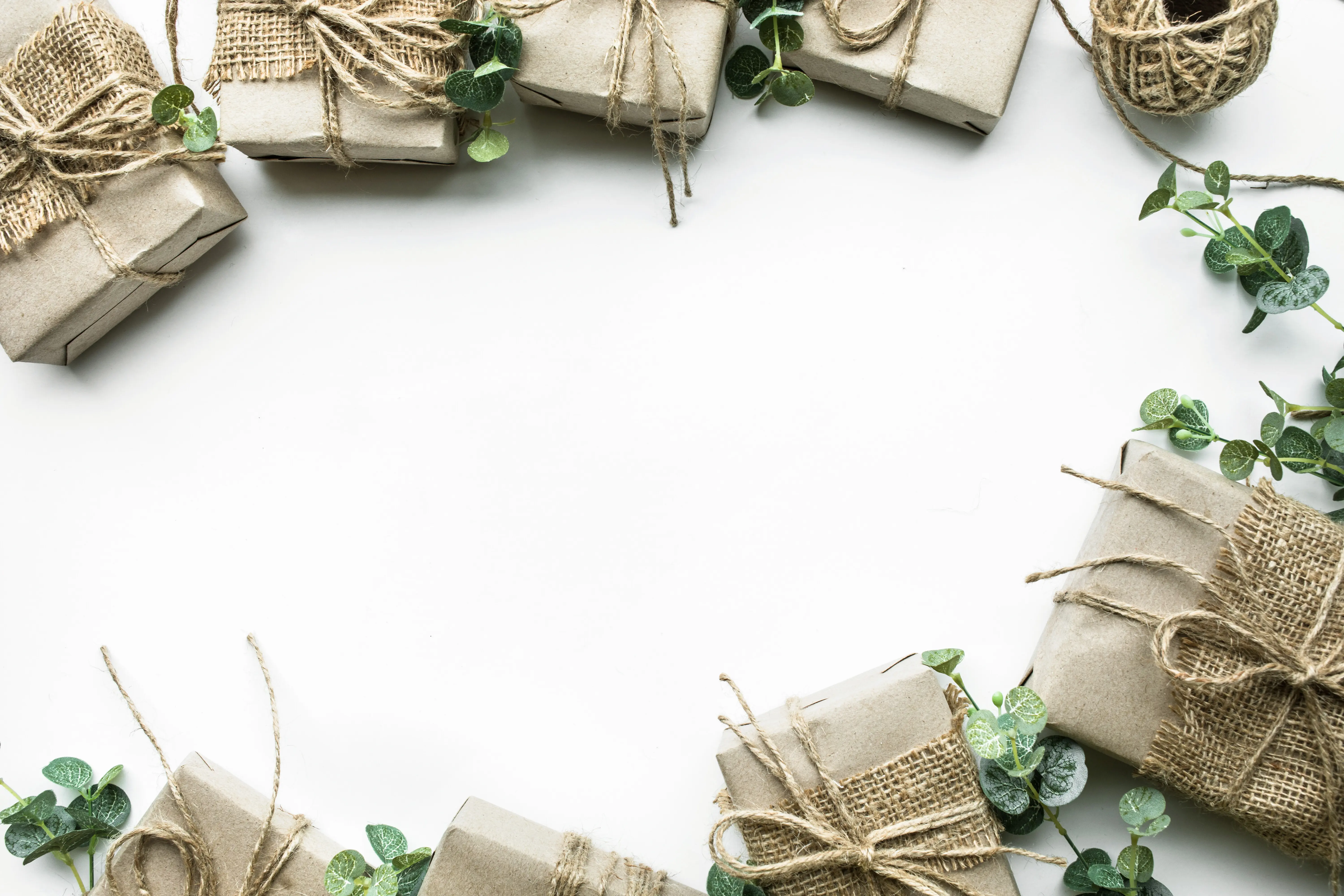 Kollektion aus in Kraftpapier verpackten Geschenkboxen im minimalistischen Stil mit Blättern auf weißem Hintergrund.